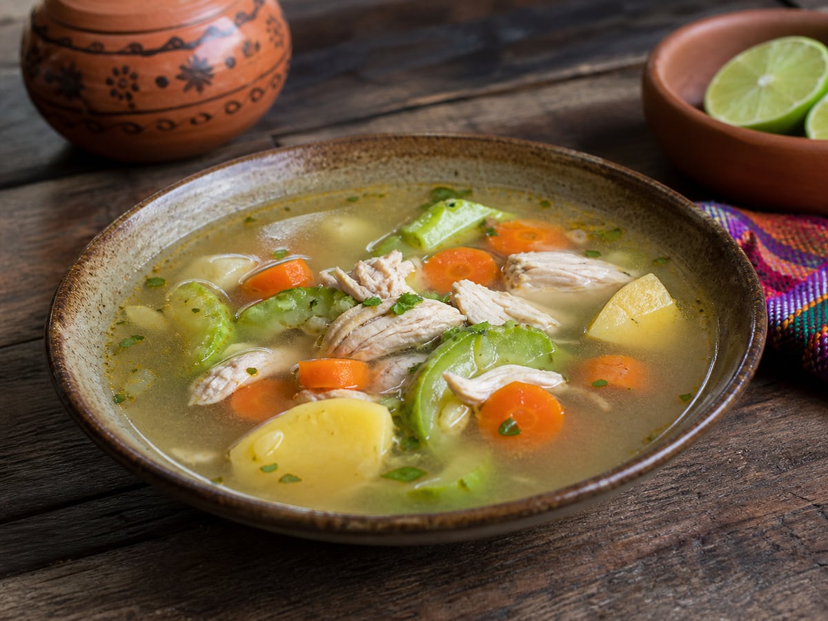 Sopa de pollo con vegetales servido en una porción casera con ingredientes visibles